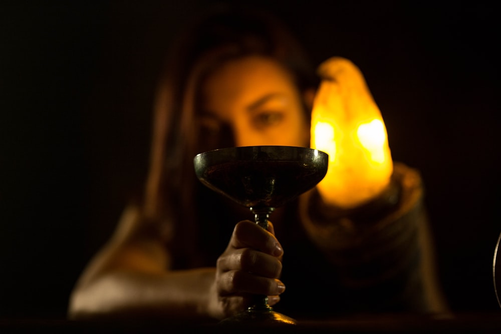 a woman holding a wine glass in front of a candle