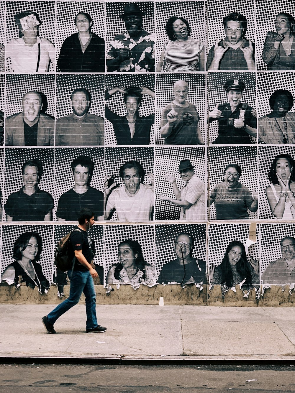 man walking on pathway near wall with different photos