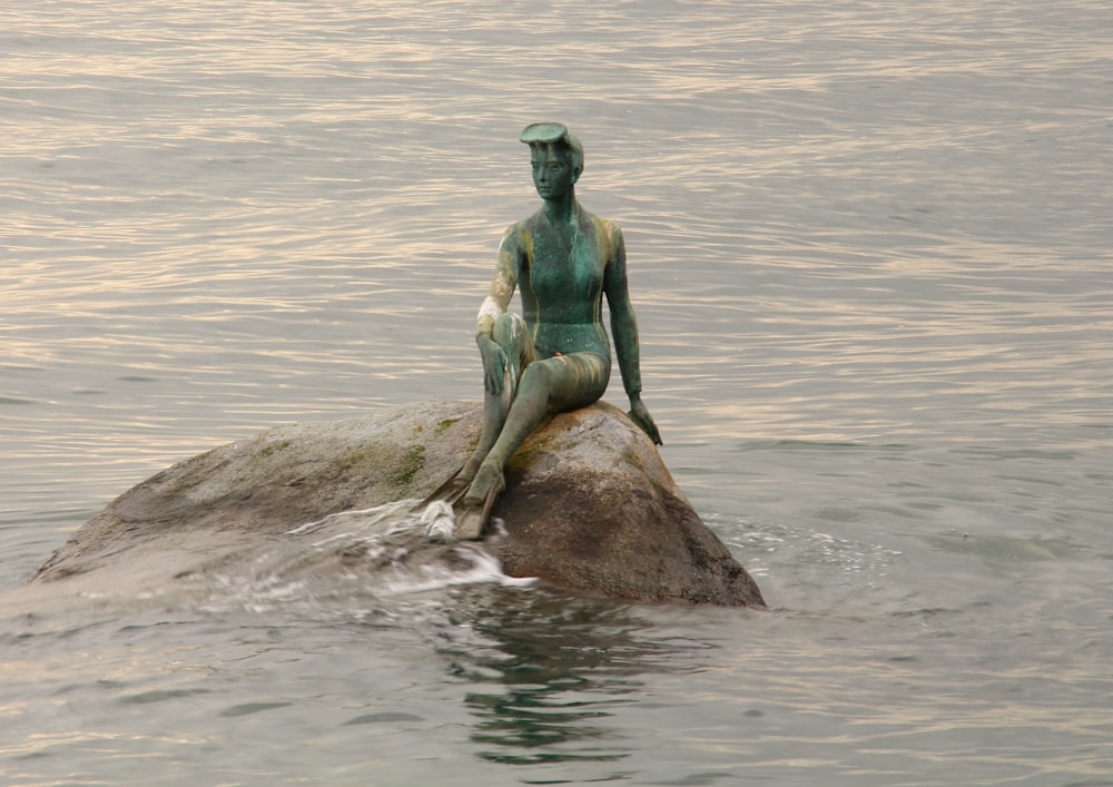 person sitting on rock surrounded by ocean