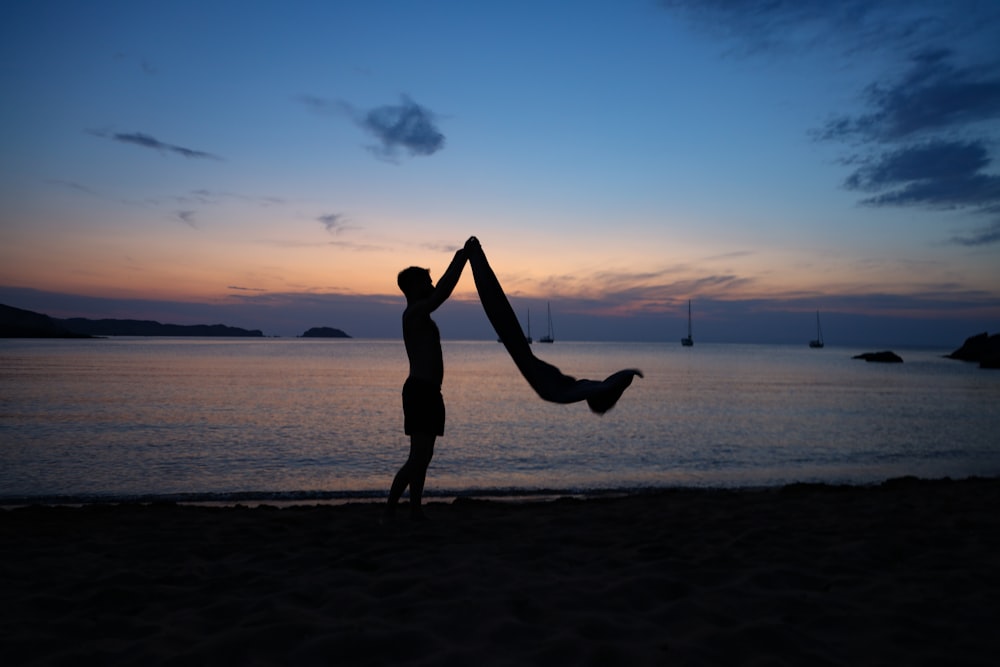 man holding textile on seashore during day