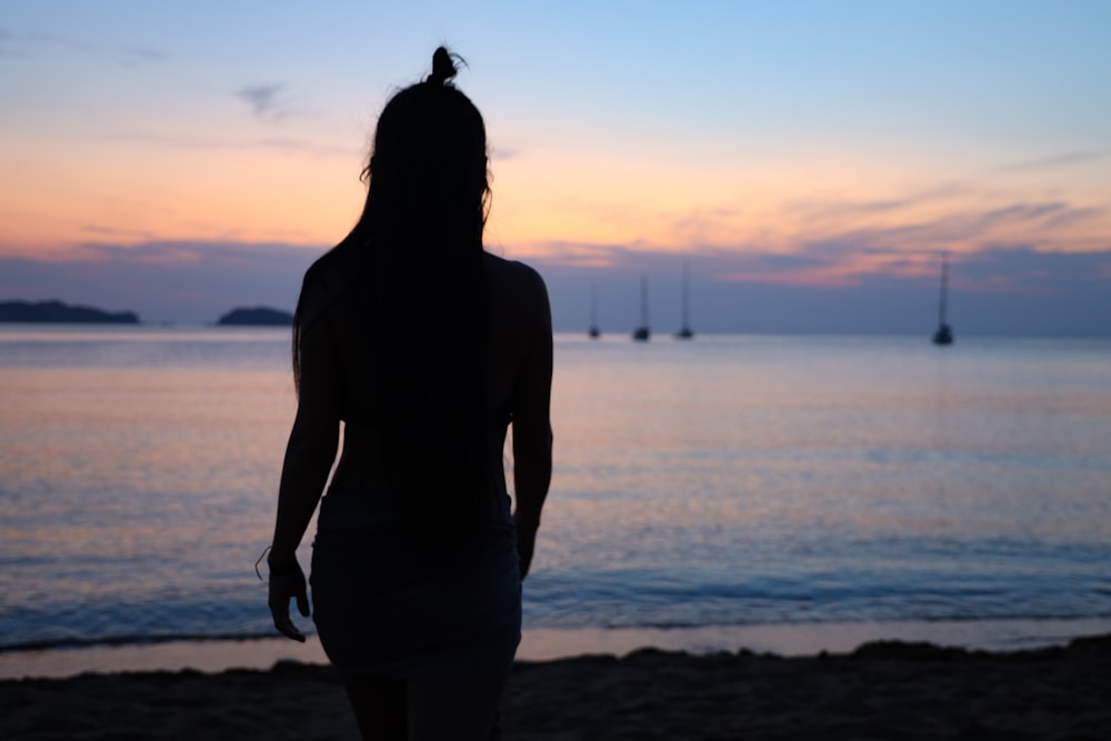silhouette photography of woman standing on seashore