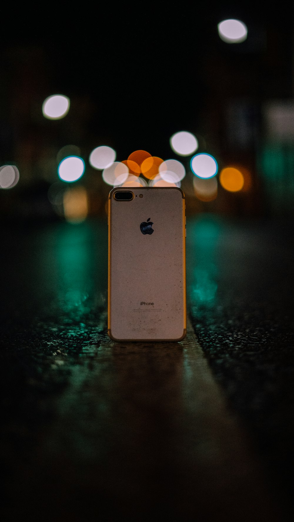 rose gold iPhone 8 Plus standing upright in the middle of the road during night