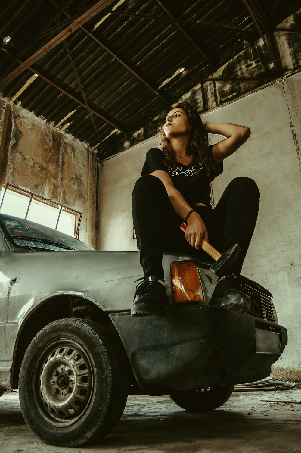 woman sitting on car hood inside garage