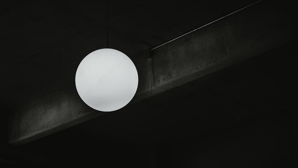 a round light hanging from a ceiling in a dark room