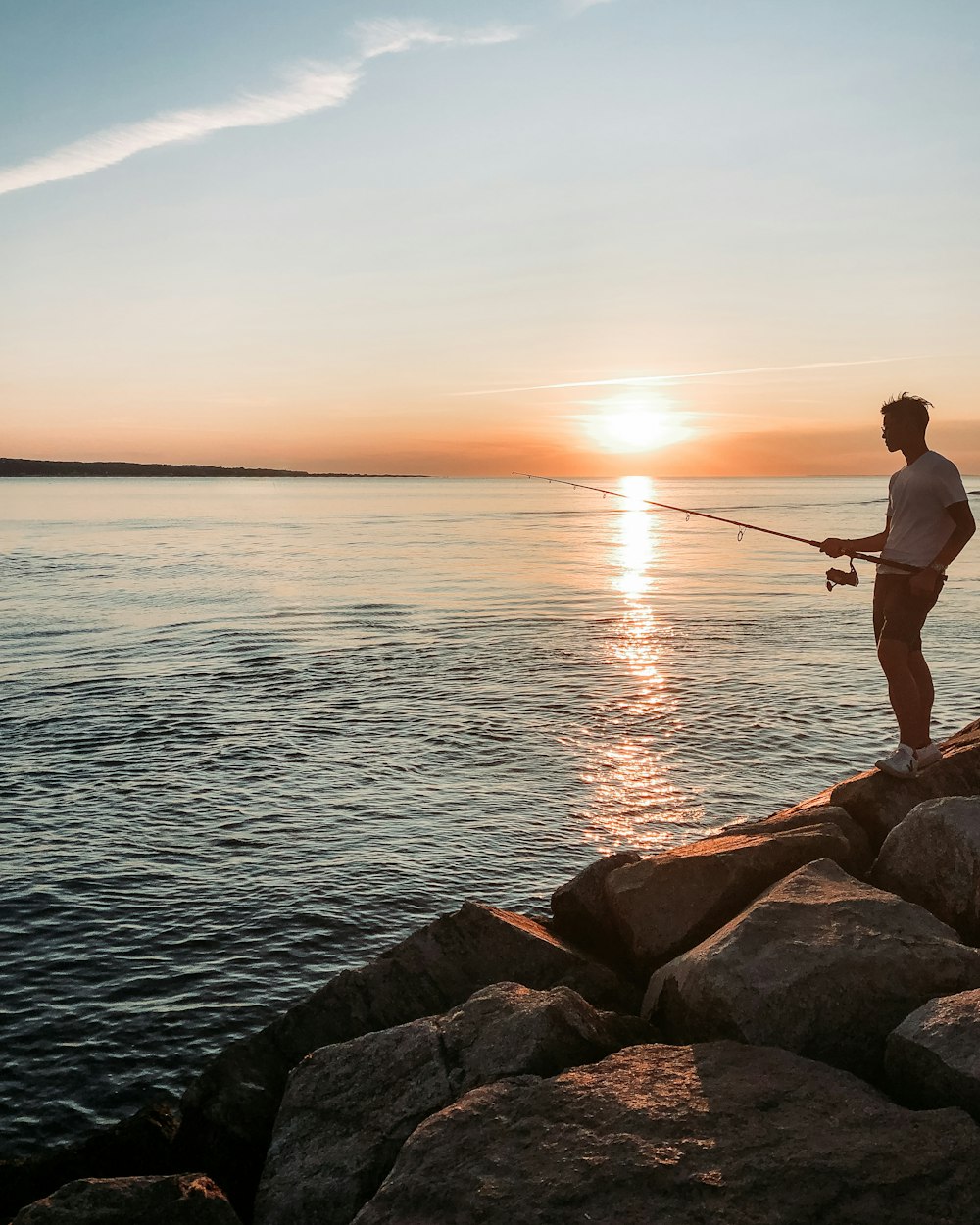 man fishing beside lake