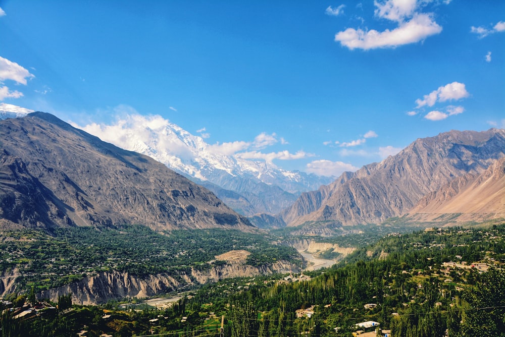 aerial photography of green field viewing mountain under blue and white skies during daytime