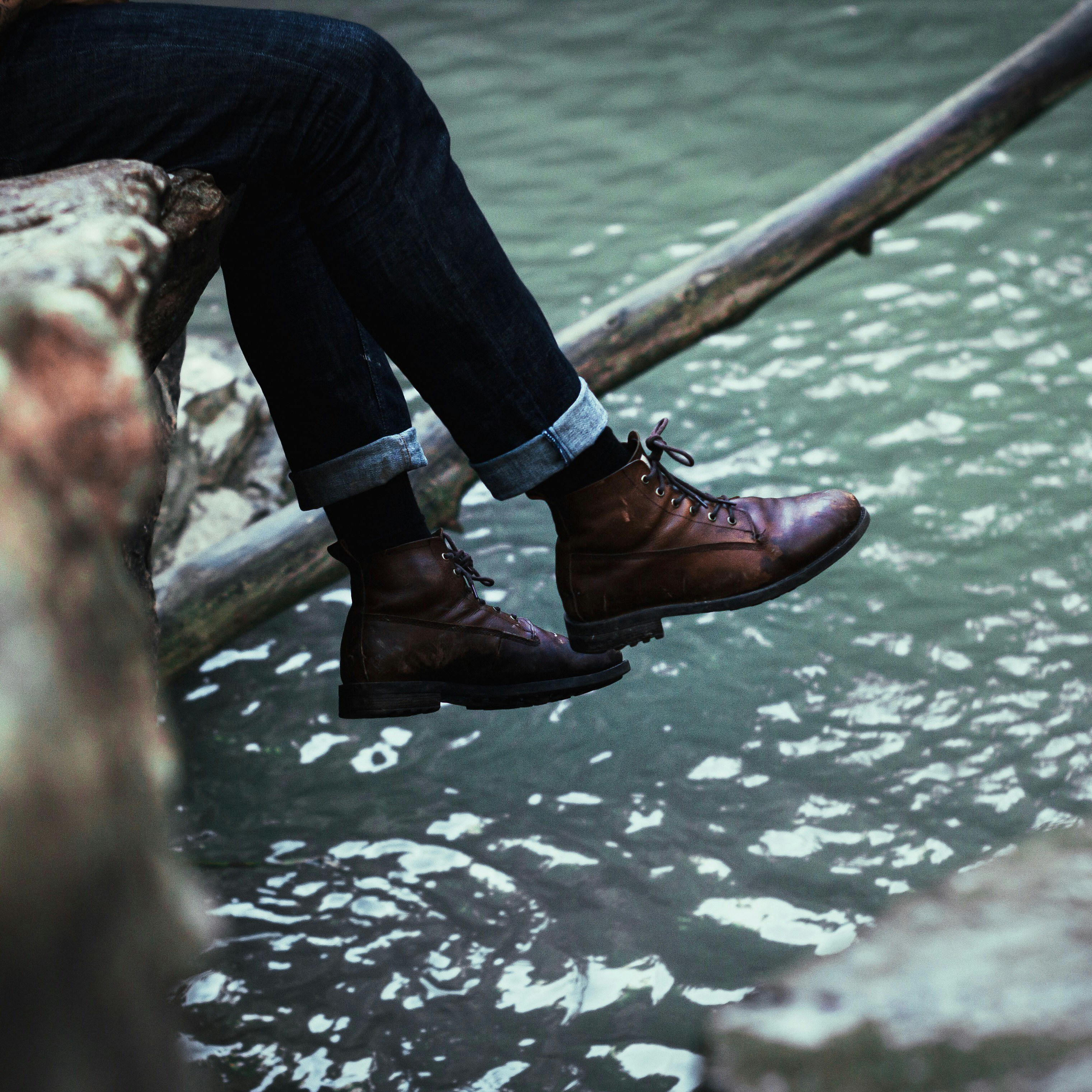 sitting person wearing black jeans and brown leather boots