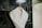 A white bathrobe is neatly hung on a wooden hanger against a textured dark green marble tiled wall. The robe appears plush and soft, suggesting comfort and luxury.