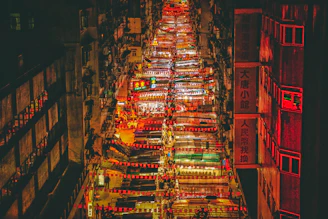 A bustling street market at sunset with colorful lights and lively crowds.