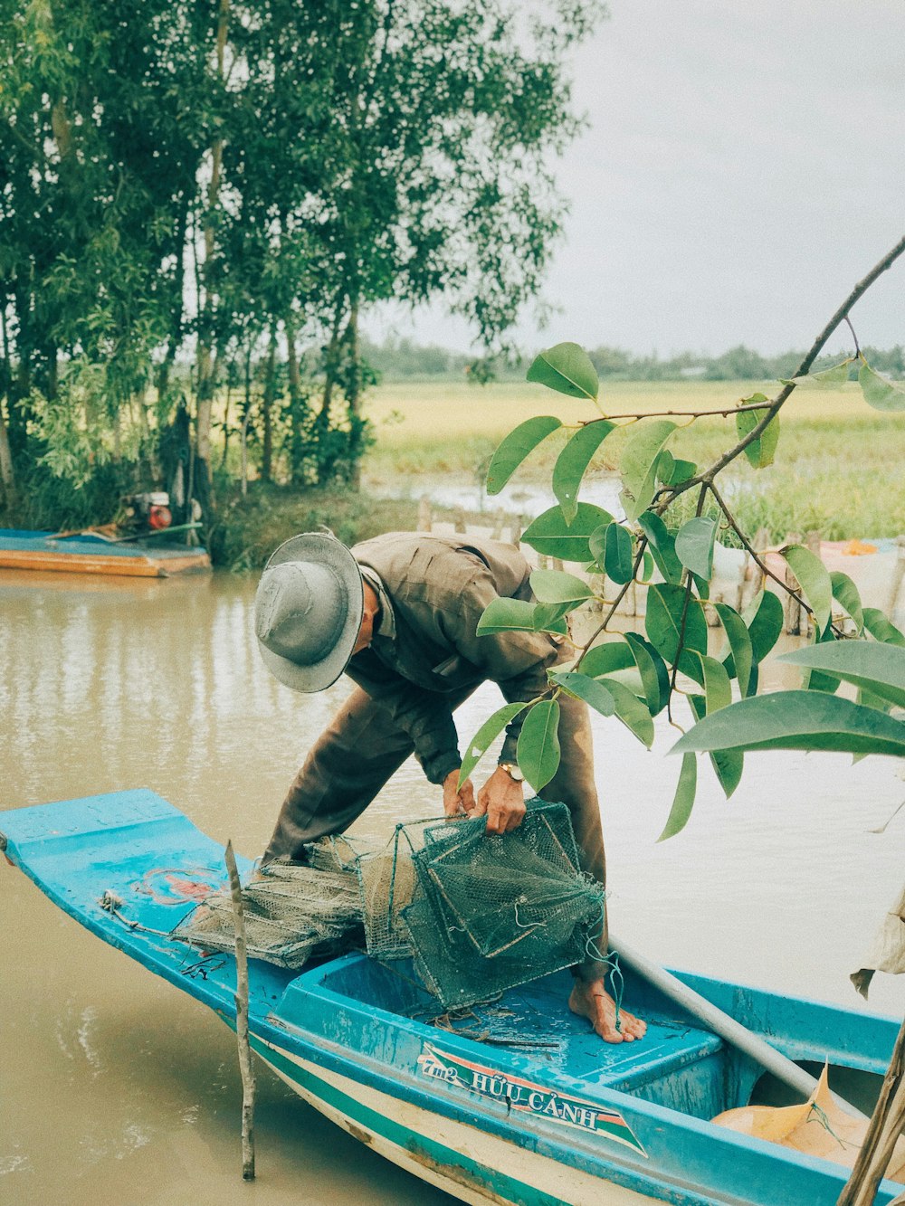 man standing on boat holding fish nets