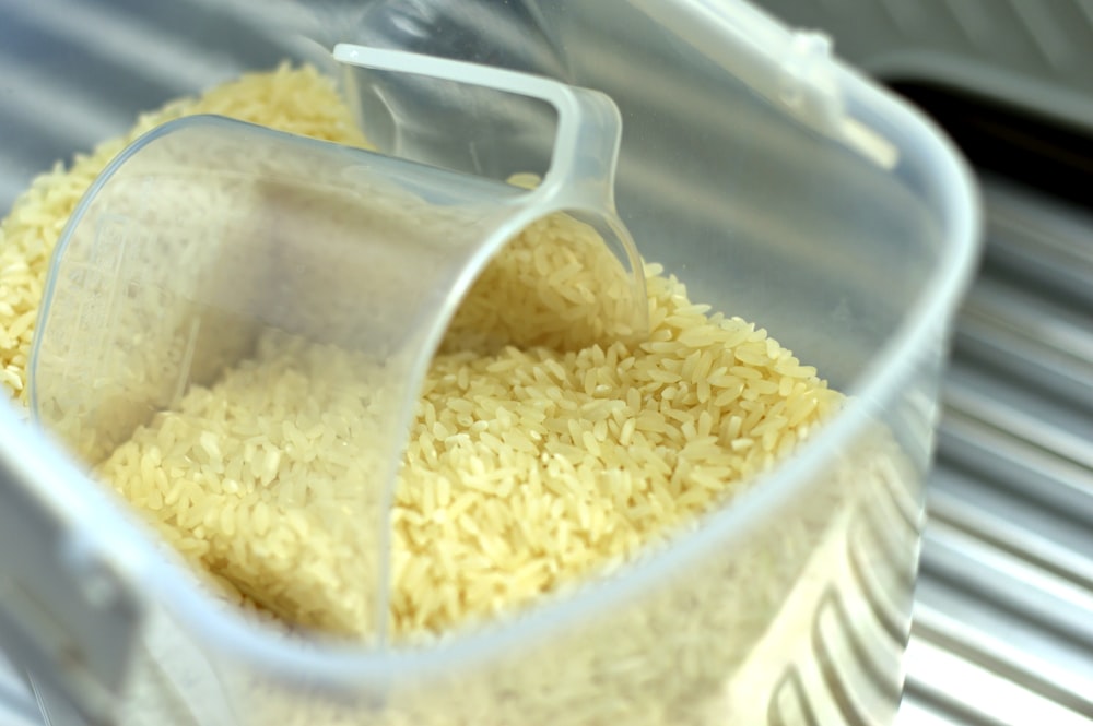 Granos de arroz con cuchara dosificadora en recipiente