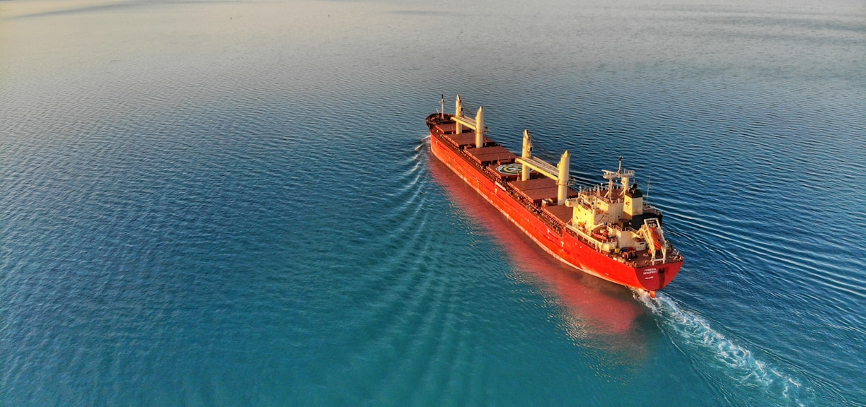 red and white cargo ship at middle of ocean