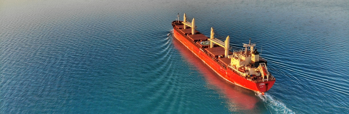 red and white cargo ship at middle of ocean