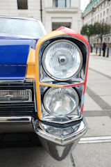 Close-up of a vintage car's detailed headlight with reflections of nearby architecture.