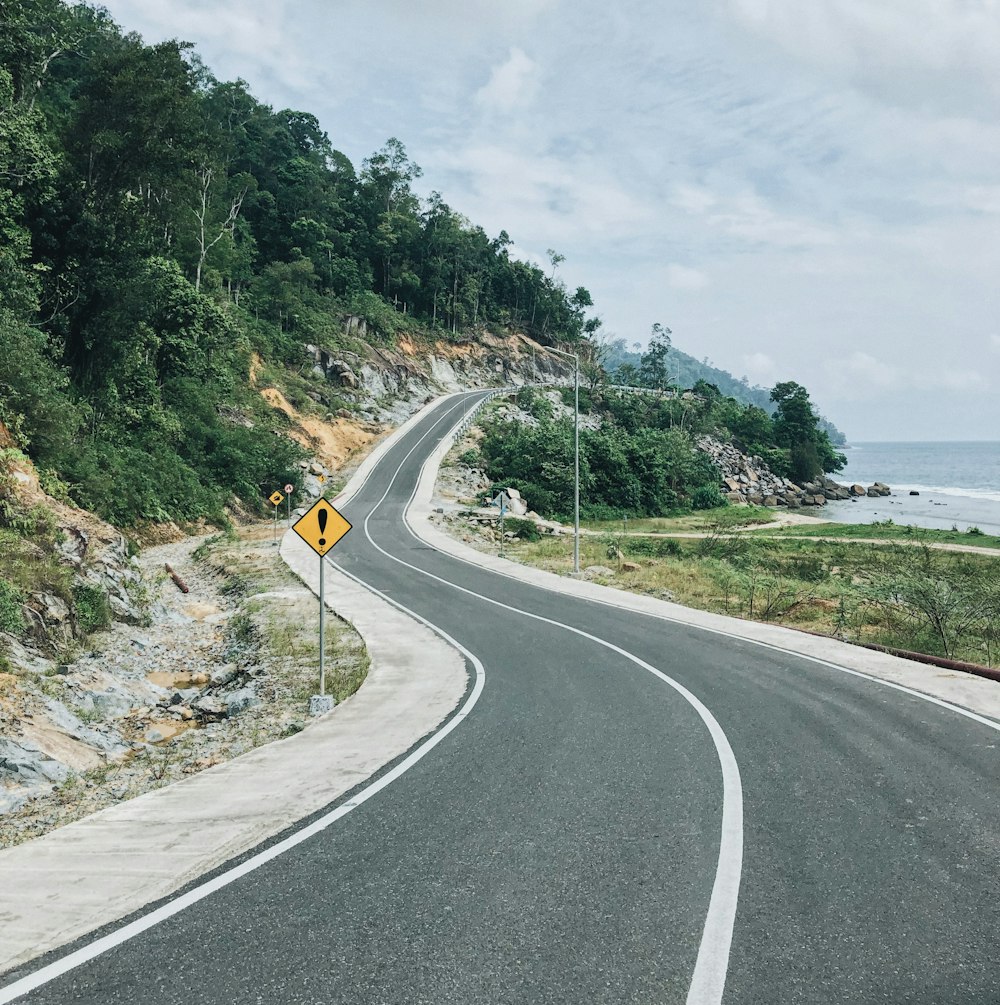 gray concrete road with no vehicle viewing blue sea during daytime