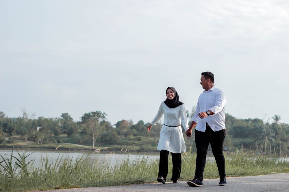 man and woman walking while holding hands each other during daytime