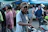 A smiling man wearing a handblocked short sleeve shirt in a sunny outdoor market.