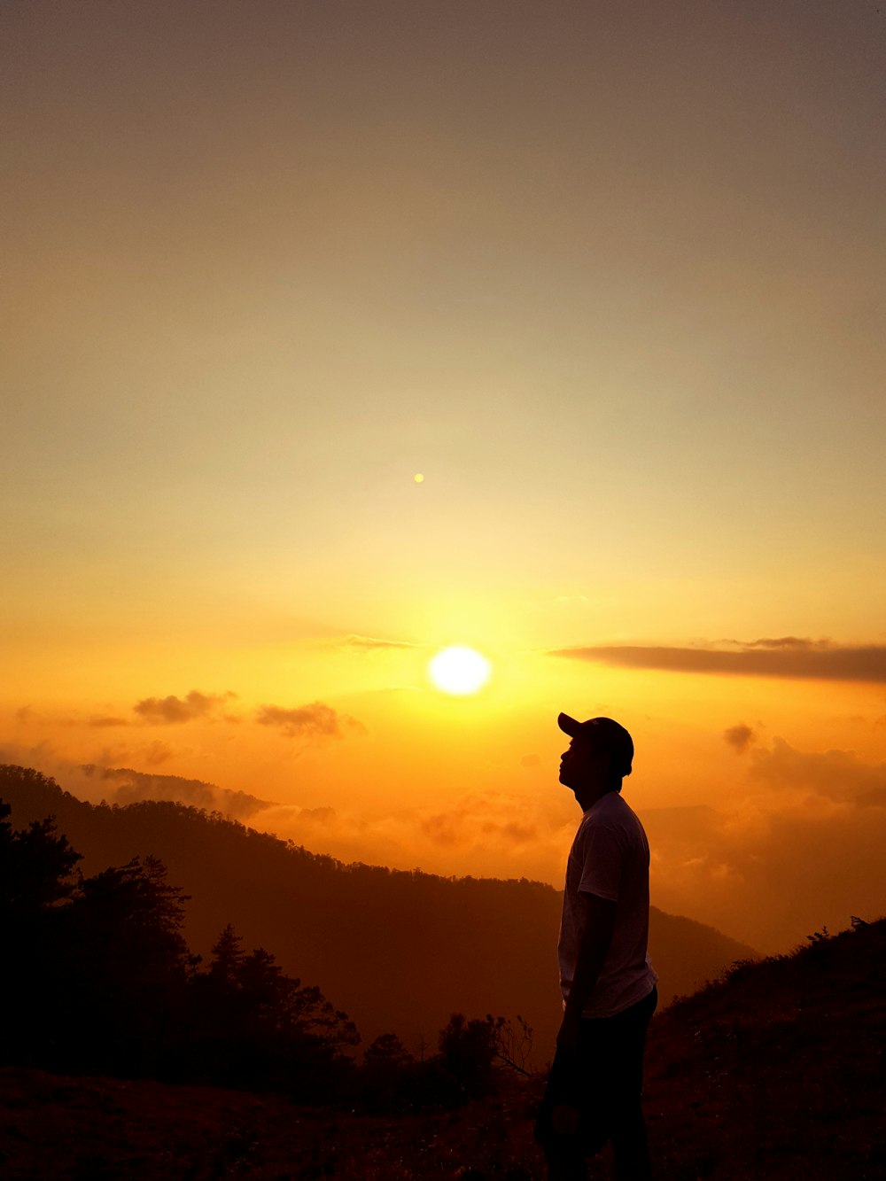man standing on top of mountain during golden hour