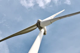 Close-up of wind turbine blades rotating gently against a clear blue sky.
