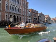 A rustic wooden boat drifting near colorful houses along the canals of Venice.