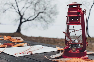 Rustic lantern glowing softly on a wooden table surrounded by autumn leaves.