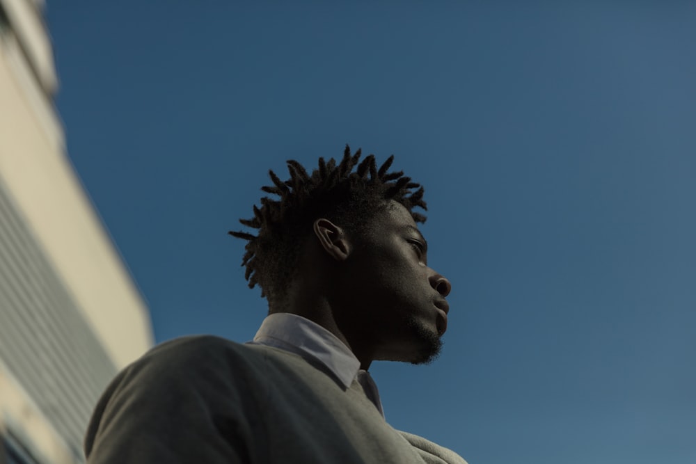 a man with dreadlocks standing in front of a building