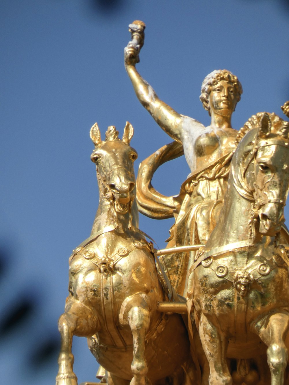 gold-colored statue of woman riding on carriage