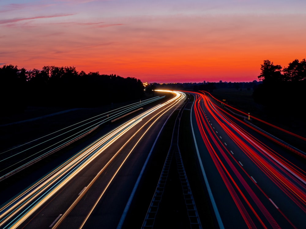 회색과 주황색 하늘 아래 도로의 타임랩스 사진