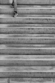 grayscale photo of person's foot on staircase