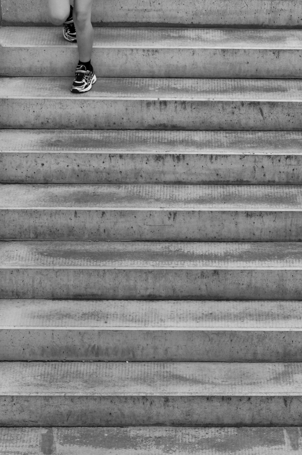 grayscale photo of person's foot on staircase