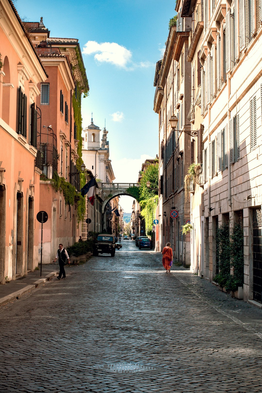 two person walking beside brown and white buildings