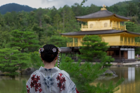 woman standing beside lake in Kinkaku-ji Japan