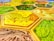 A close-up view of a board game with hexagonal tiles featuring different landscapes such as fields, forests, and deserts. The tiles exhibit vibrant colors and detailed textures with each hexagon bordered distinctly.