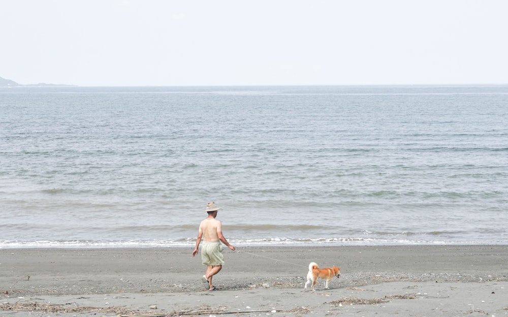 개 옆에서 해변을 걷는 남자
