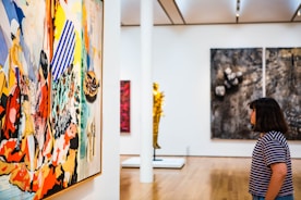 woman standing and facing a painting on wall inside gallery