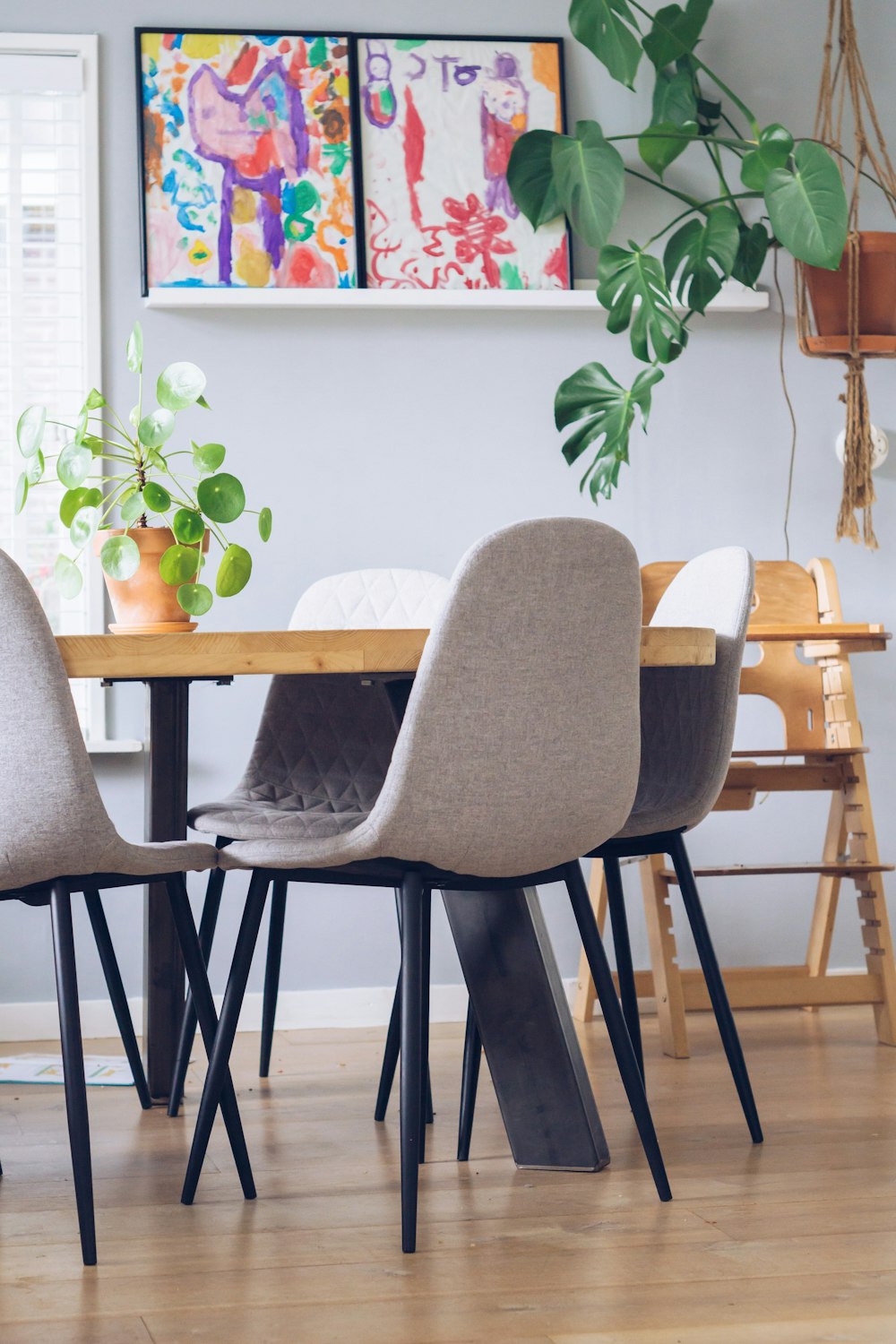 a dining room table with four chairs and a potted plant