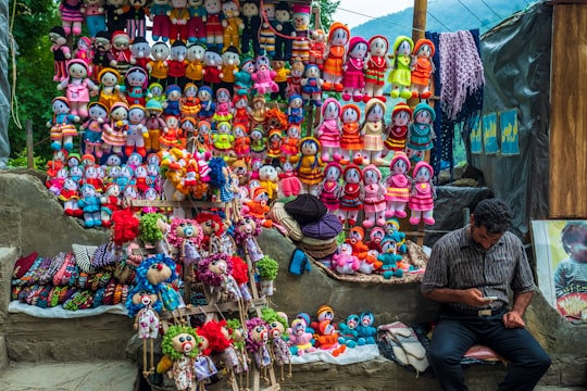 man sitting beside assorted-color display item in Masooleh Iran