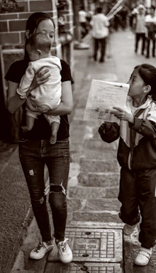 grayscale photo of woman carries baby near girl
