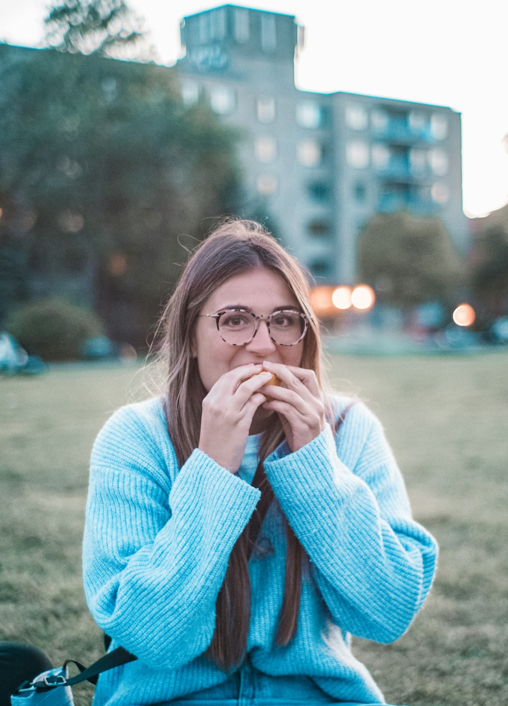 Mujer en suéter azul comiendo al aire libre