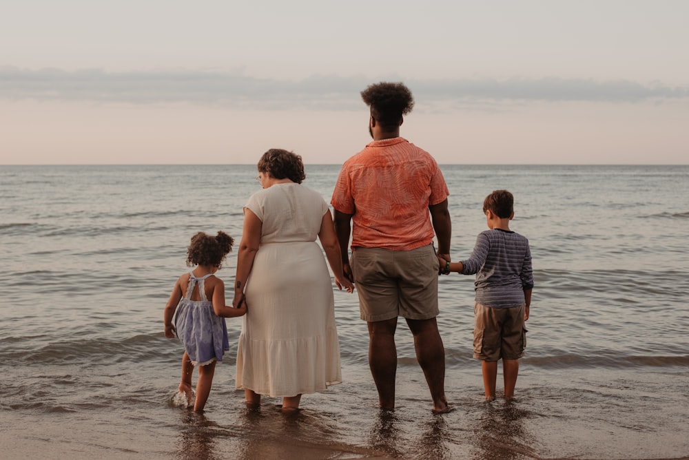 four people standing on seashore