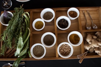 Fresh Ayurvedic herbs and powders arranged neatly on a wooden tray.