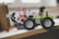 A toy tractor made from colorful interlocking plastic blocks, featuring black wheels and a green body. It has a movable arm ending in a claw, which is predominantly red and white.