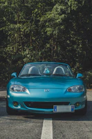 blue Mazda Miata convertible coupe on road during day