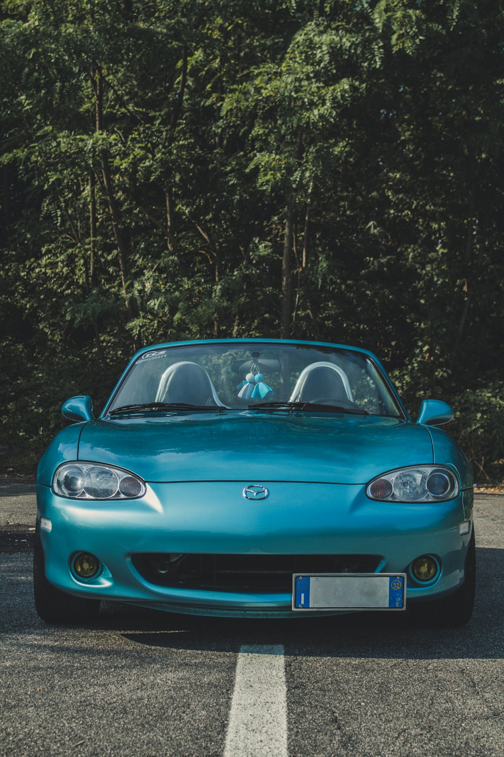 blue Mazda Miata convertible coupe on road during day