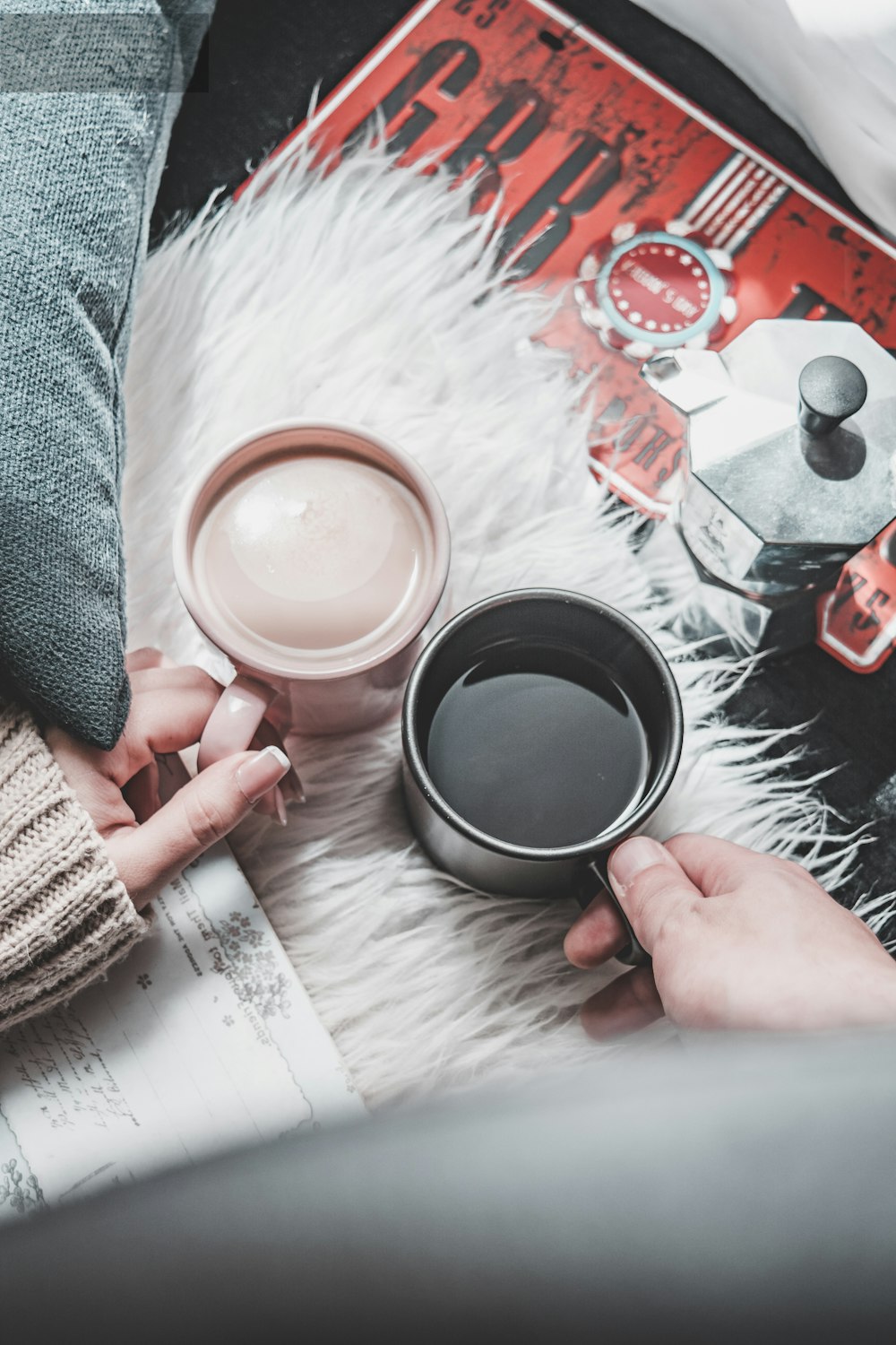 two person holding brown and black mugs