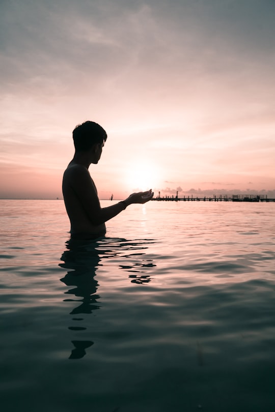 silhouette of man standing in sea during golden hour in Isla Mujeres Mexico