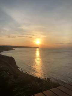 A serene sunset over the Sicilian coast, capturing the golden light and calm sea.