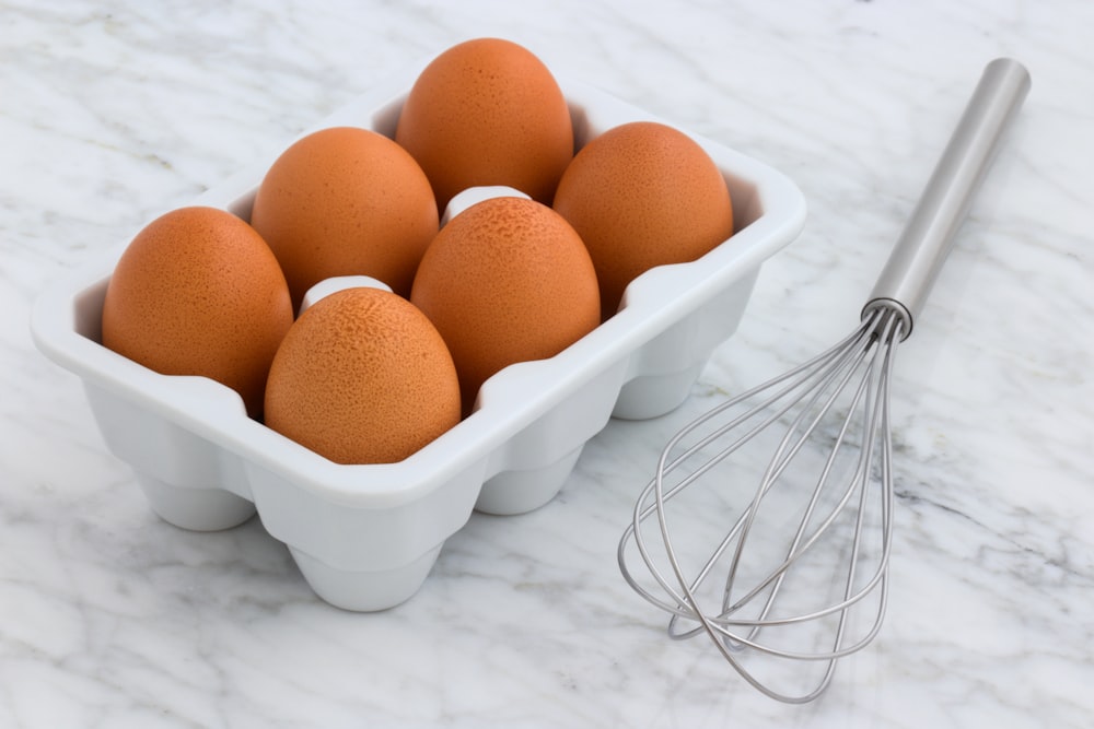 Packung Bio-Eier neben silbernem Schneebesen