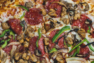 A vibrant close-up of a supreme pizza loaded with pepperoni, sausage, ham, green peppers, and onions, fresh from the oven.