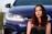 a woman sitting in front of a blue car